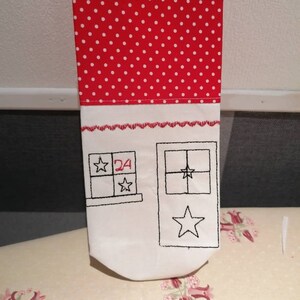 May include: A white fabric advent calendar with red polka dot fabric on the top. The calendar has a window with a star and a number 24.