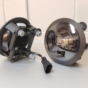 Puede incluir: Dos luces LED redondas negras con una lente transparente. Las luces tienen un cable negro con un conector en el extremo. Las luces están diseñadas para uso todoterreno.
