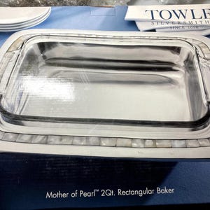 Könnte beinhalten: Rechteckige Backform mit einem transparenten Glaseinsatz und einem silberfarbenen Metallrahmen. Der Rahmen ist mit einer Perlmutt-Intarsie verziert. Die Form hat Griffe und ist mit "Mother of Pearl 2Qt. Rectangular Baker" beschriftet.