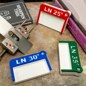 May include: Three white plastic angle guides for sharpening tools. The guides are labeled "LN 25°", "LN 30°", and "LN 35°".