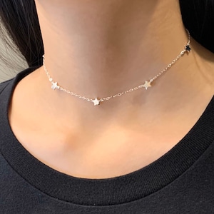 May include: A silver chain choker necklace with five small star charms.