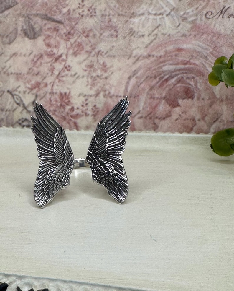 Op de afbeelding: Een zilveren ring met een gedetailleerd ontwerp van twee engelenvleugels.