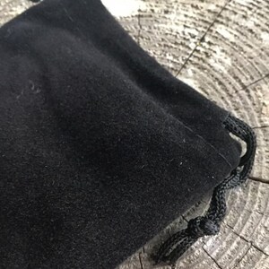 May include: A black velvet drawstring pouch with a black cord.