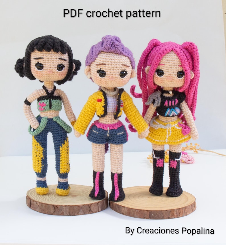 May include: Three handmade crochet dolls with different hairstyles and outfits. The dolls are standing on wooden bases. The text "PDF crochet pattern" is at the top of the image, and "By Creaciones Popalina" is at the bottom.