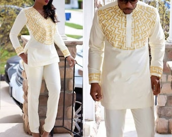 May include: A white long-sleeved shirt with a gold geometric pattern. The shirt has a mandarin collar and a button closure. The shirt is paired with white trousers.