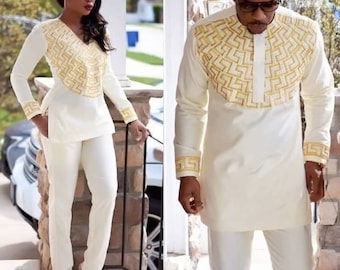 May include: A white long-sleeved shirt with a gold geometric pattern on the front and cuffs. The shirt is paired with white trousers.