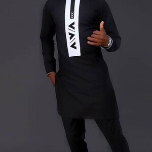 May include: A black long-sleeved shirt with a white vertical panel featuring a geometric design and the text "V/AV" and "ooo". The shirt is paired with black trousers.