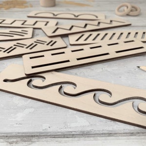 May include: A set of wooden stencils featuring a variety of patterns, such as waves, zigzags, and lines. The stencils are crafted from light brown wood and have a smooth finish.