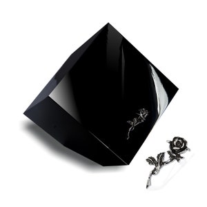 Peut inclure: Une boîte carrée noire avec un motif de rose argentée sur le dessus. Une rose argentée séparée avec des accents noirs est également représentée.