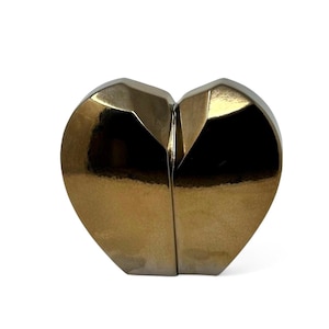May include: A gold heart-shaped sculpture with a geometric design. The sculpture is made of metal and has a shiny finish.