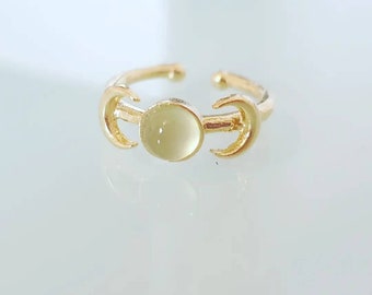 May include: Gold-toned adjustable ring featuring a pale yellow gemstone center. The ring's design incorporates crescent moon shapes on either side of the gemstone, creating a celestial theme. The ring is open at the back for adjustability.