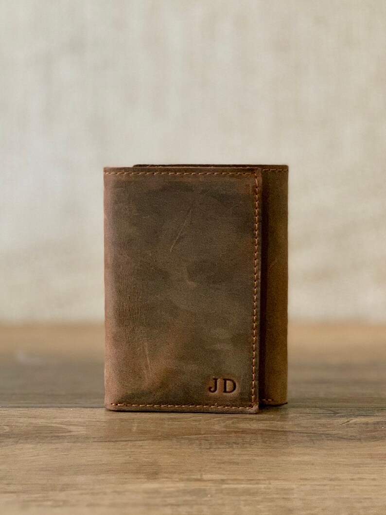 May include: A brown leather wallet with the initials "JD" embossed on the front.