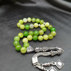 Pu&ograve; includere: Un set di grani della preghiera verdi e gialli. Le perle sono rotonde e hanno un aspetto marmorizzato. Il set include elementi decorativi in metallo color argento e un nappa.