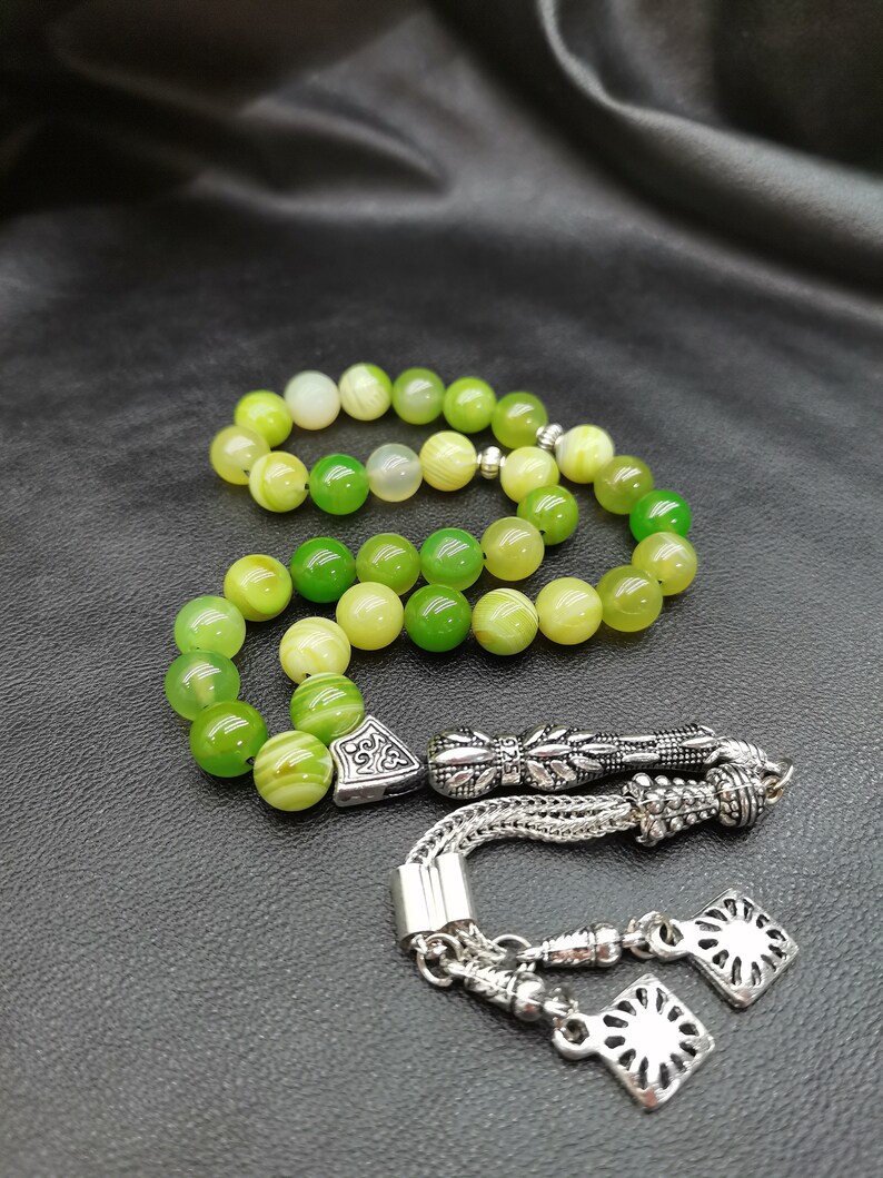 Pu&ograve; includere: Un set di grani della preghiera verdi e gialli. Le perle sono rotonde e hanno un aspetto marmorizzato. Il set include elementi decorativi in metallo color argento e un nappa.