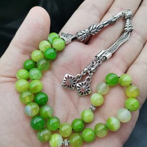 Pu&ograve; includere: Un set di grani della preghiera verdi e argentati. Le perline sono un mix di verde chiaro e scuro, con accenti argentati. Le perline sono infilate con una catena d'argento e pezzi decorativi d'argento.