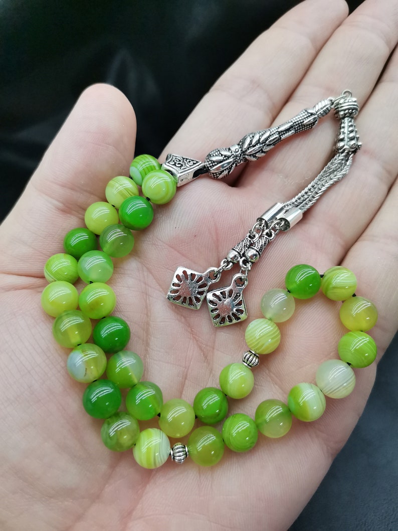 Pu&ograve; includere: Un set di grani della preghiera verdi e argentati. Le perline sono un mix di verde chiaro e scuro, con accenti argentati. Le perline sono infilate con una catena d'argento e pezzi decorativi d'argento.