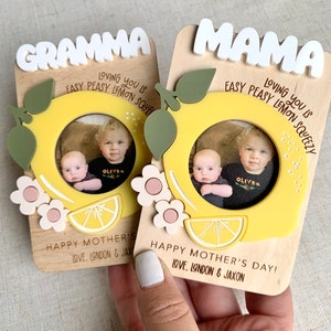 May include: Two wooden photo frames with a lemon design and the words "Grandma" and "Mama" on them. Each frame has a photo of two young boys with the name "Oliver" written on each photo. The frames have the text "Loving you is easy peasy lemon squeezy" and "Happy Mother's Day! Love, London & Jaxon" on them.