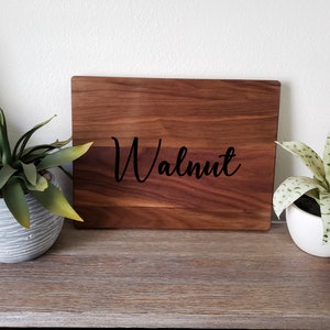 May include: A wooden cutting board with the word "Walnut" engraved in black lettering.