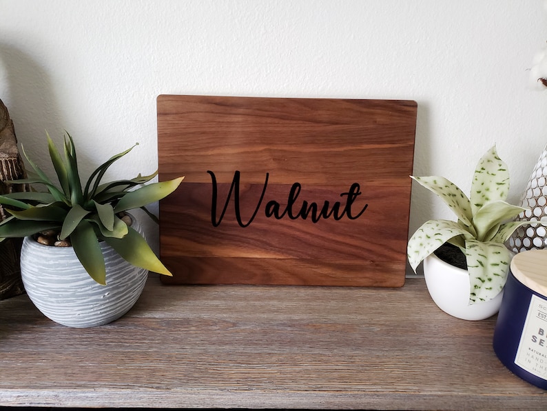 May include: A wooden cutting board with the word "Walnut" engraved in black lettering.