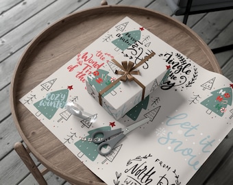 Könnte beinhalten: Ein verpacktes Geschenk mit braunem Band liegt auf einem Holztisch, umgeben von weihnachtlichem Geschenkpapier. Das Papier zeigt Weihnachtsbäume, Schneeflocken und Sätze wie "Merry Christmas" und "Let it snow". Schere und Klebeband liegen ebenfalls auf dem Tisch.