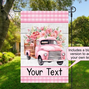 May include: Pink and white garden flag with a pink truck carrying a bouquet of pink flowers. The flag has a white wooden background with the text "Your Text" in black. Includes a blank version to add your own text.