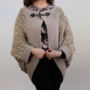 May include: A beige crocheted cardigan with a brown button closure. The cardigan has a loose fit and a slightly cropped length.