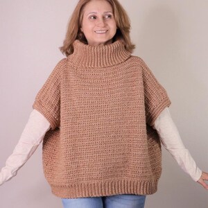 May include: A brown crocheted turtleneck sweater with a loose fit and short sleeves.