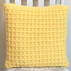 May include: A yellow crocheted pillow with a waffle stitch pattern.