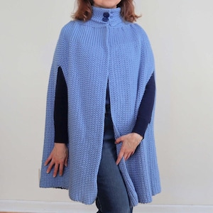 Puede incluir: Una capa de punto azul claro con cuello alto y cierre de botón. La capa tiene un diseño largo y fluido y está hecha de una tela suave y cómoda.