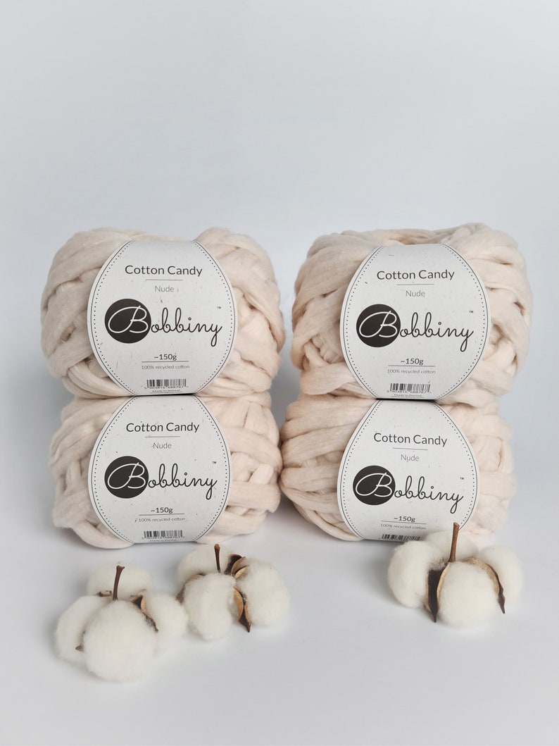 May include: Four balls of nude colored cotton candy yarn, each weighing 150 grams. The yarn is made of 100% recycled cotton. The yarn is labeled "Cotton Candy" and "Bobbiny".