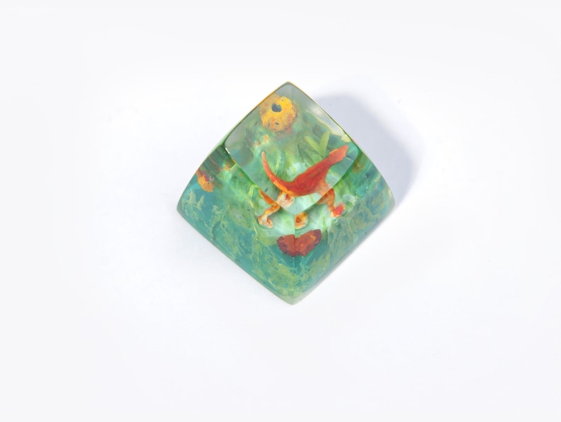May include: A clear green and yellow resin cube with a red and yellow fish design inside.