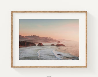 May include: A panoramic view of a rocky coastline with a misty, pink-hued sky at sunset. The ocean waves are crashing on the shore, creating a sense of tranquility and beauty.
