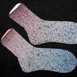 Op de afbeelding: Twee paar sokken in een blauw en paars ombre-patroon met witte stippen.