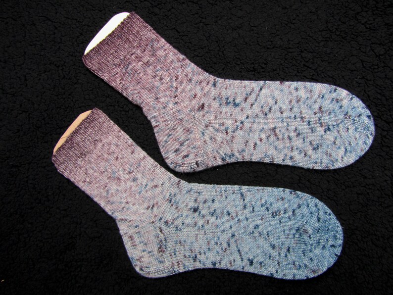 Op de afbeelding: Twee paar sokken in een blauw en paars ombre-patroon met witte stippen.