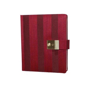 Peut inclure: Un journal à rayures rouges avec une serrure et un trou de serrure dorés. Le journal a un rabat qui recouvre la serrure.