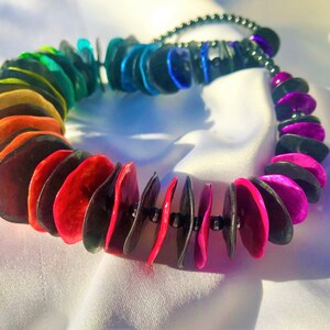 Unikt regnbågsfärgat halsband med flerfärgade och svarta modellerade tunna plattor, handmålade, med ett färgspel med hematitpärlor.