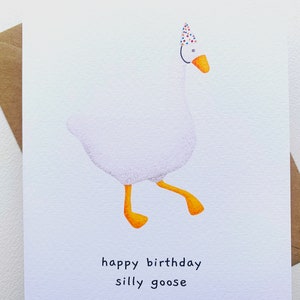 K&ouml;nnte beinhalten: Eine wei&szlig;e Gans mit einem bunten Partyhut und dem Text "happy birthday silly goose" auf einer wei&szlig;en Karte.
