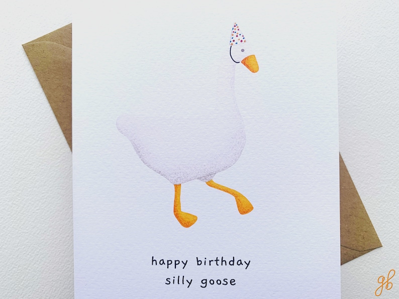 K&ouml;nnte beinhalten: Eine wei&szlig;e Gans mit einem bunten Partyhut und dem Text "happy birthday silly goose" auf einer wei&szlig;en Karte.