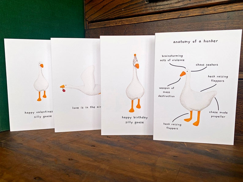 May include: Four white greeting cards featuring goose illustrations. One card reads "happy valentines silly goose", another says "love is in the air", a third says "happy birthday silly goose", and the last is an anatomy diagram of a goose.