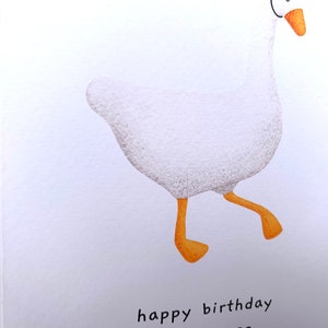K&ouml;nnte beinhalten: Eine wei&szlig;e Gans mit orangefarbenen Beinen und Schnabel geht mit einer Happy Birthday-Botschaft auf wei&szlig;em Hintergrund.