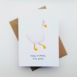 K&ouml;nnte beinhalten: Eine wei&szlig;e Gans mit einer Partym&uuml;tze mit roten und wei&szlig;en Punkten. Die Gans geht mit ausgestreckten F&uuml;&szlig;en. Der Text "happy birthday silly goose" ist unter der Gans gedruckt.