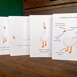 May include: Four greeting cards featuring a cartoon goose with different captions. The first card says "Happy Valentines Silly Goose". The second card says "Love is in the air". The third card says "Happy Birthday Silly Goose". The fourth card says "Anatomy of a Honker" and has a diagram of the goose with labels for its different features.