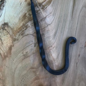 May include: A black metal stocking holder with a twisted design. The holder is shaped like a hook with a rounded end.