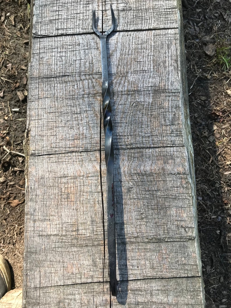 Może przedstawiać: Czarny metalowy szpikulec z zakręconym uchwytem i tr&oacute;jzębną końc&oacute;wką.