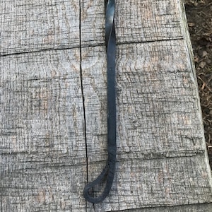 Może przedstawiać: Czarny metalowy poker do kominka ze skręconym uchwytem i pętlą na końcu.