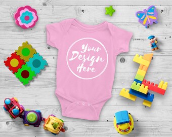 Download Free Blank Pink Baby Onesie Mockup, Fashion Design Styled, Baby Mock up with Toys - Flat, Direct View on Wood Background - JPG Download PSD Template