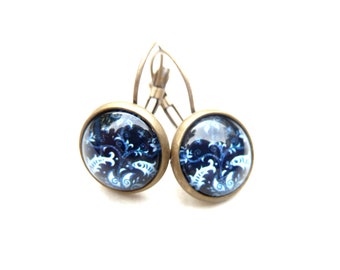 Earrings made of bronze-colored metal with a glass cabochon with blue background and white fish