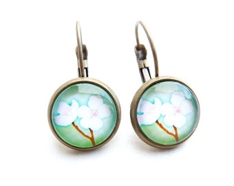 Flower power earrings with a glass cabochon of white flowers on a light green background