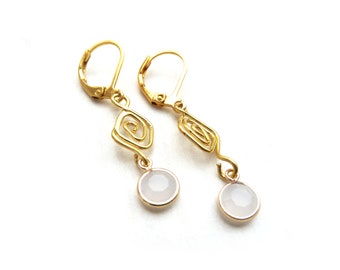 Gold-colored earrings with spiral ornament and a white opaque colored facet pendant with an acrylic stone