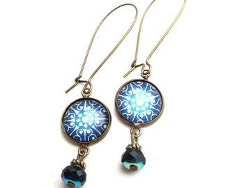 Boucles d'oreilles avec un cabochon en verre avec illustration blanche sur fond bleu, terminé par une perle de verre facettée noire